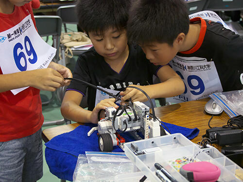 小学生も熱心に参加-チームで力を合わせてロボットを組み立てる.jpg